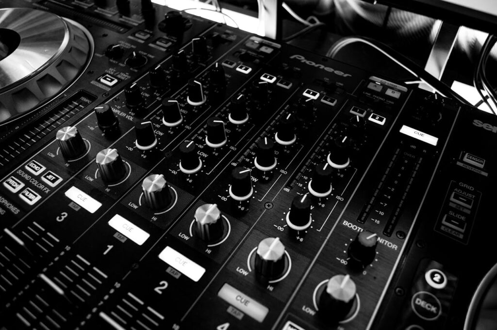 pexels photo 63703 Black and white close-up of a DJ's audio mixing console with knobs and controls.
